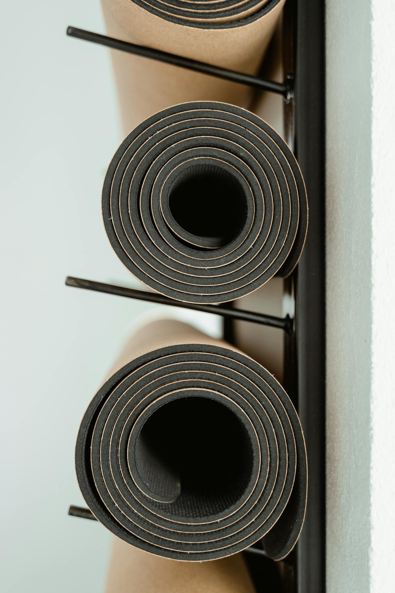 Rolled yoga mats neatly stacked on a rack indoors, ideal for fitness or wellness themes.